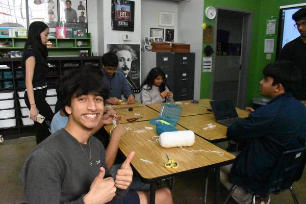 A member giving a thumbs up while making paper garden kits